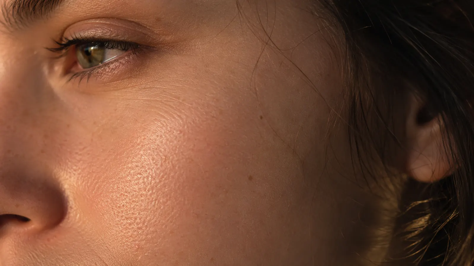 Close-up of smooth skin texture on a cheek area with small visible pores, suggesting improved but not erased pore appearance