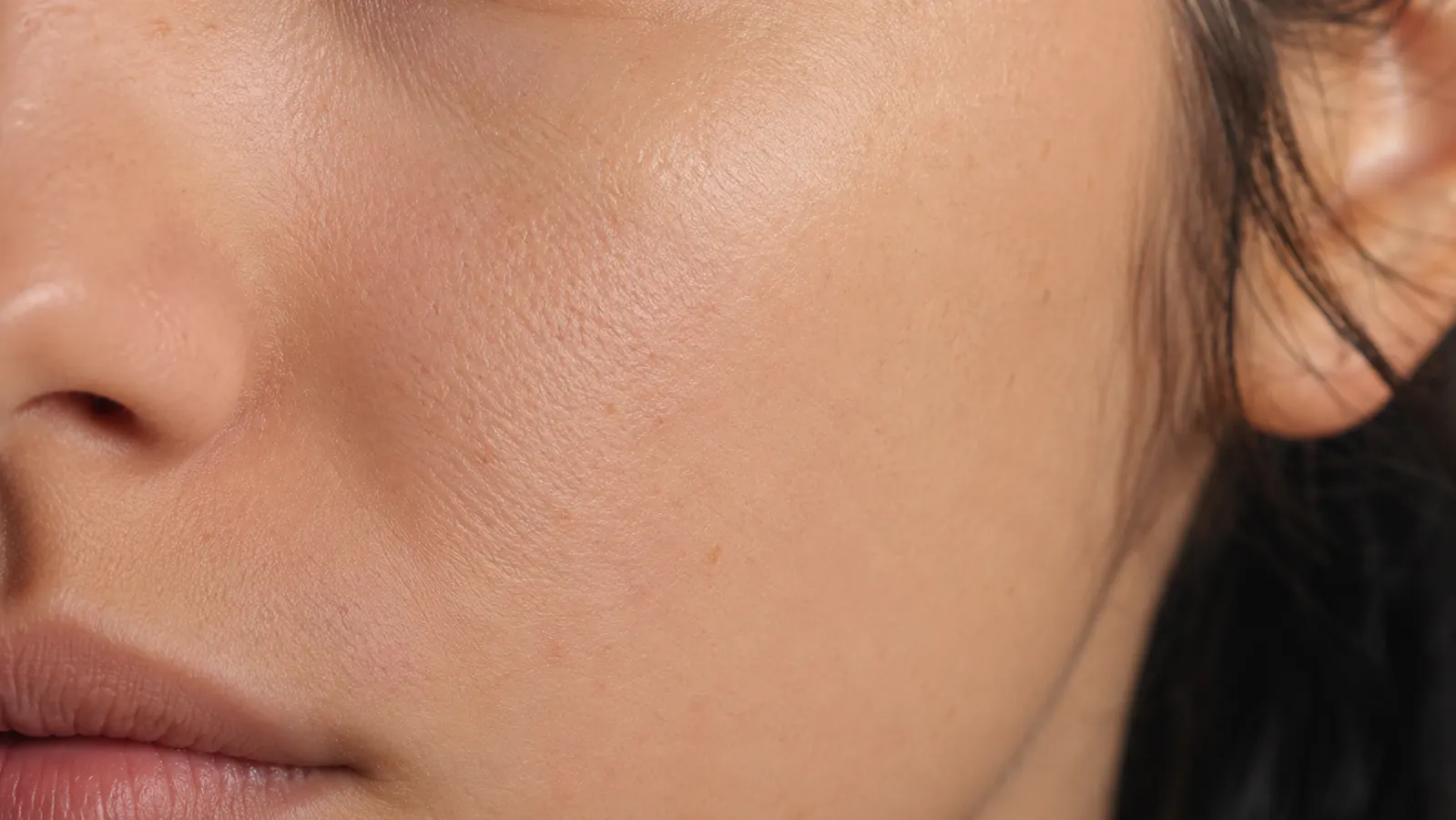 Close-up of skin texture on a clean, lightly freckled cheek showing refined pores